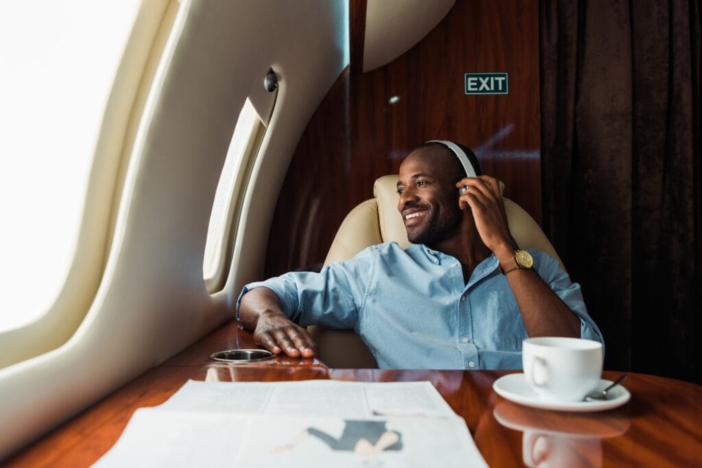 selective focus of happy african american man listening music in private plane